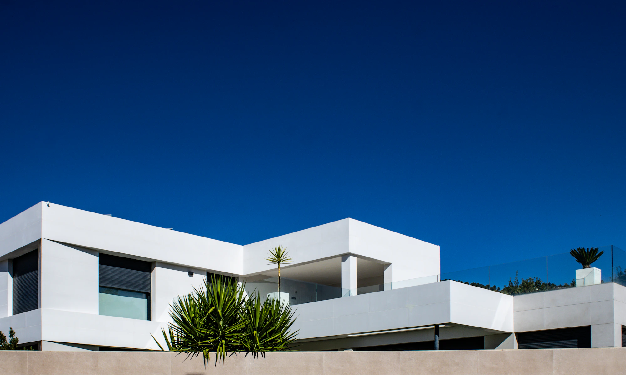 Modern white rendered house with broad horizontal rooflines and dark windows