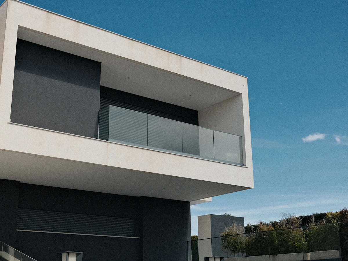 Contemporary white rendered home with a shaded upper balcony and dark accents